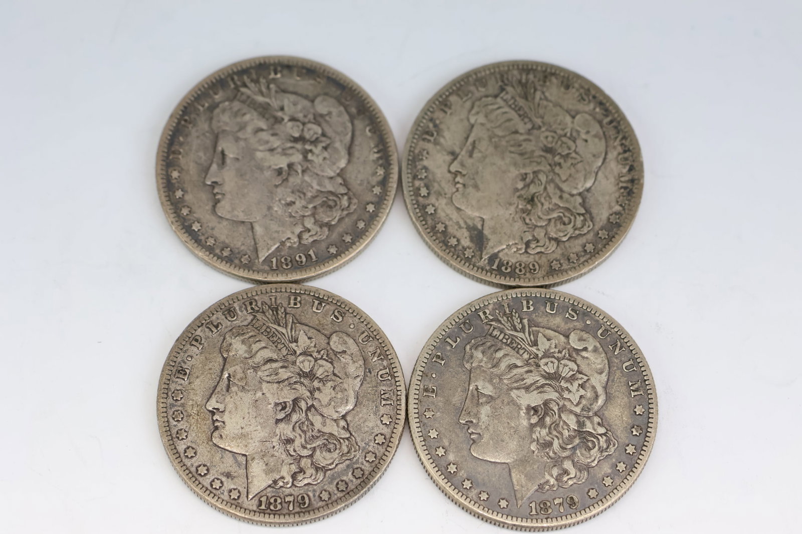 Four 1800's Morgan Silver Dollars: Four 1800's Morgan Silver Dollars Four 1800's Morgan Silver Dollars. Comprising two 1879, one 1889-O, and 1891. Used condition, wear, worn.