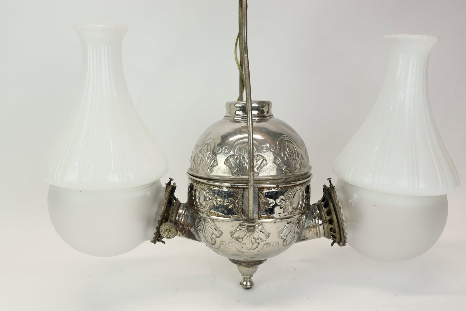 Antique Double Arm Angle Lamp: Antique Double Arm Angle Lamp Antique Double Arm Angle Lamp. Double burner fluid hanging lamp converted to electric with a foliate embossed metal body and milk glass lamp shades. Frosted glass globes