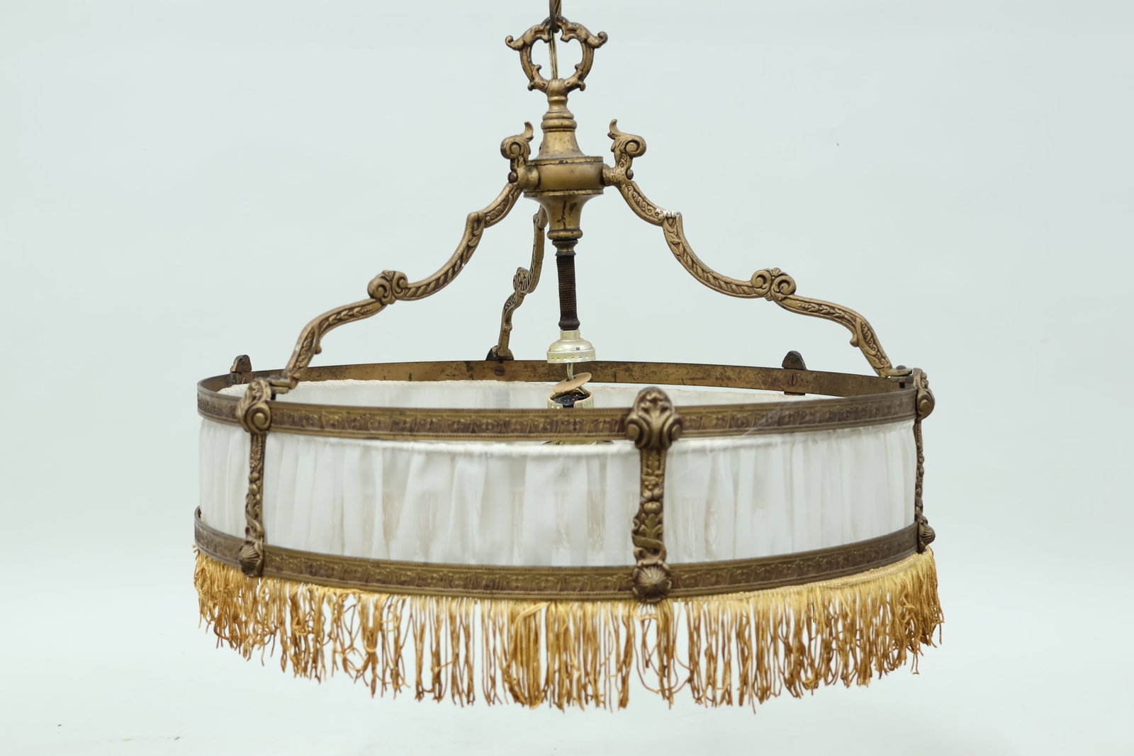 Neo-Classical Style Drum Chandelier: Neo-Classical Style Drum Chandelier Neo-Classical Style Drum Chandelier, with patinated metal frame, fabric panel and fringe border. Used condition, wear, worn and measuring 15' high x 21" diameter.