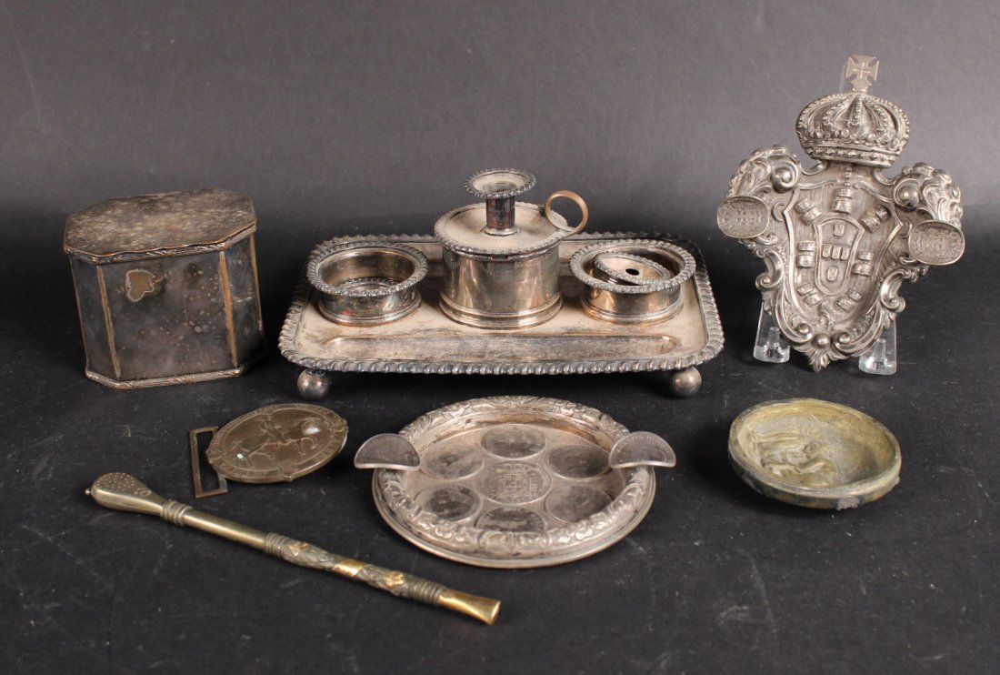English Coin Decorated Ashtray: Together with silver plated inkstand, a shield, hinged box, brass erotic dresser lid, a belt buckle, and a 800 silver muddler.