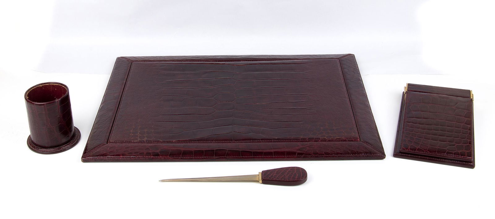 GUCCI DESK SET Late 60s/Early 70s: GUCCI DESK SET Late 60s/Early 70s â€˜Ringâ€™ Marine Crocodile skin Desk set, Bordeaux color and gilt lever clocks, composed by desk, block notes holder, pen holder and letter opener. Measures