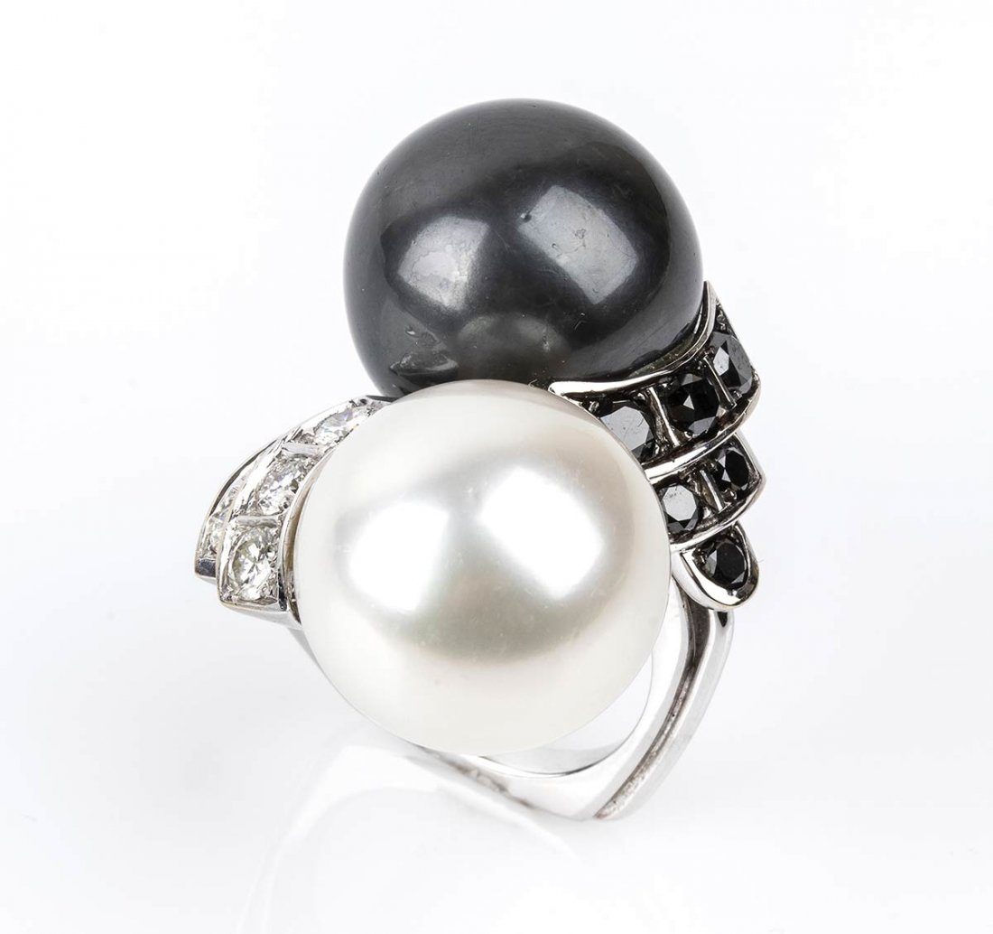Gold, pearl and black and white diamonds ring: 18k white gold, with Australian and Thaitian pearl flanked by brilliant cut pavÃ© set diamonds ca. 1.15 ct total, F-G, VVS and black diamonds ca. 1.20 ct. Stamped "750". Front dimensions 40 x 30 mm,