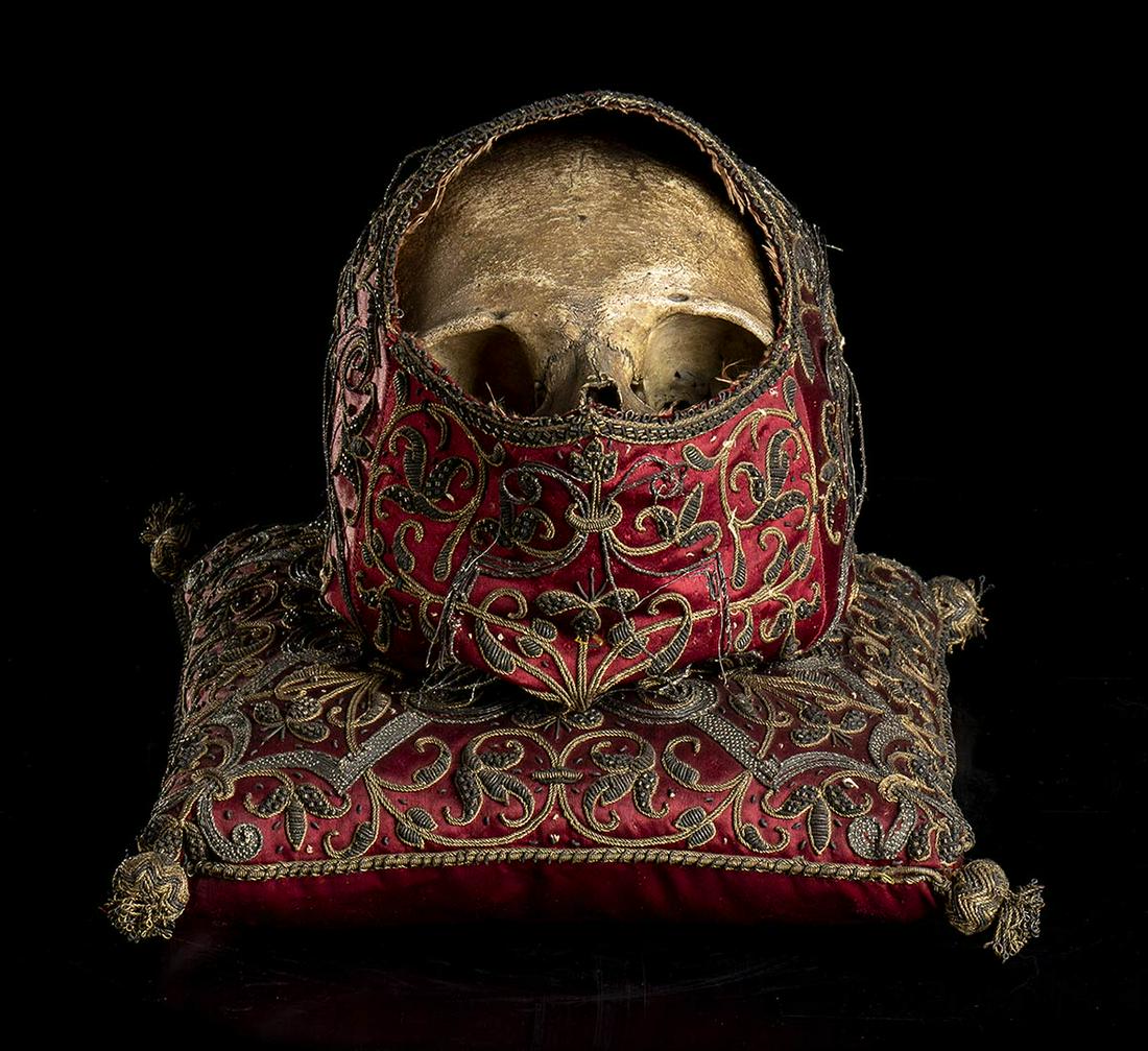 RENAISSANCE SKULL: Real medieval or Renaissance skull kept inside a fabulous hood embroidered by hand with gold and silver thread. The hooded skull rests on a beautiful pillow with the same style and materials. Datable 