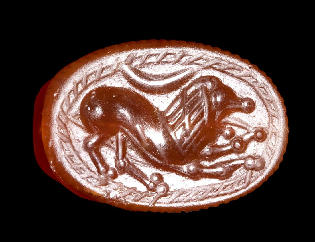AN ETRUSCAN CARNELIAN SCARAB. LION WITH CRESCENT MOON.: AN ETRUSCAN CARNELIAN SCARAB. LION WITH CRESCENT MOON. 3rd century B.C.9x14x6,5 mmThe animal is facing right, with open mouth and tongue out, in a pose reminiscent of the Chimera. Moon crescent above.