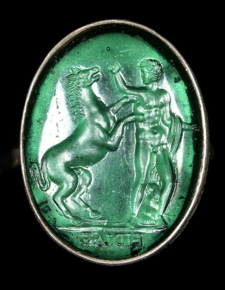 A GREEN GLASS IMPRESSION SET IN A SILVER RING - FOB. MAN WITH AN HORSE. (1 of 2)