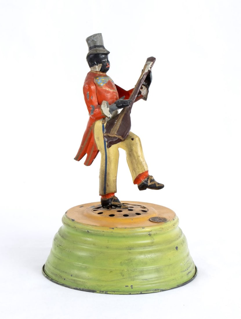 Gunthermann Banjo player: Hand-painted tin automaton, wind up, Banjo player, black character as it was common in the period 1880-1920 to find musical bands made up of black players. On a semi-conical base, with internal music