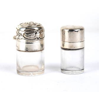 A pair of cut crystal and sterling silver bottles: both feature a hinged clasp and a small glass stopper, as does the base. One is distinguished by its smooth surface, while the other is embellished with decorations of winged putti. - Decorated jar: s