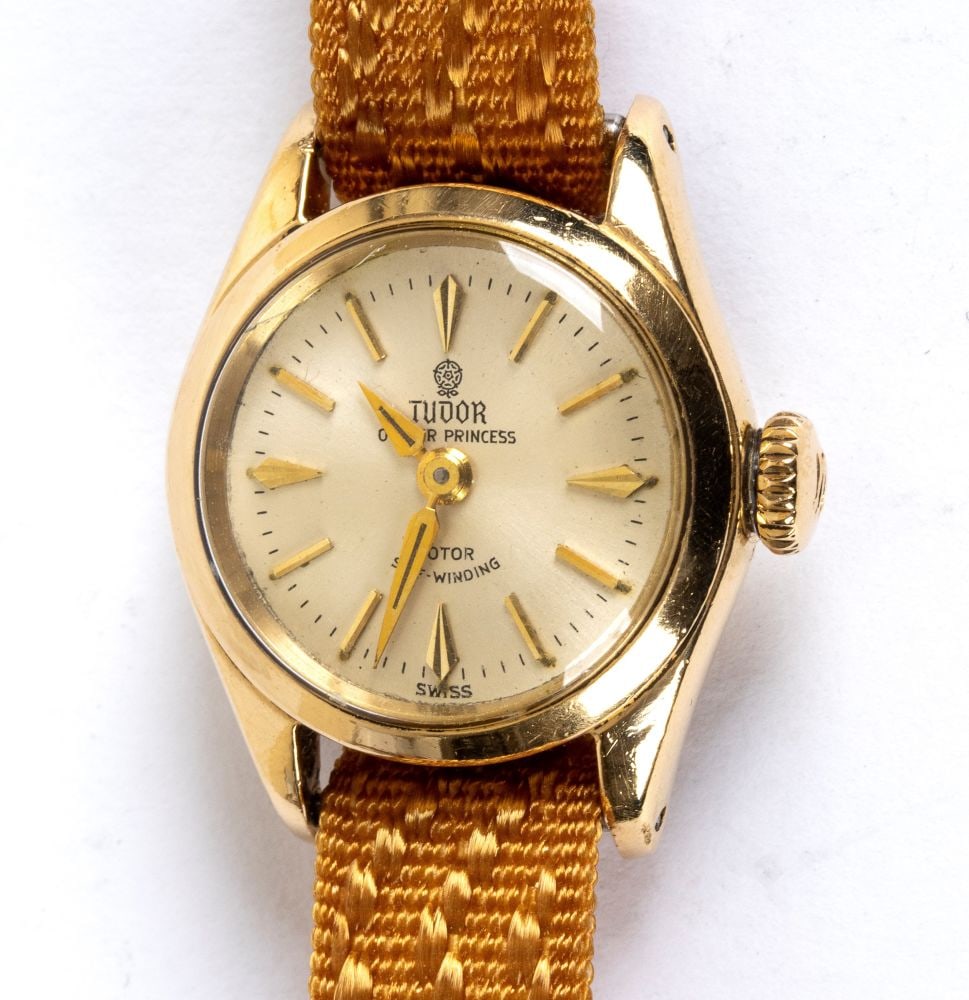 TUDOR () Gold Lady wristwatch -: gold oyster case, mechanical self-winding movement, false base, silver-plated dial with ‘gladio’ ball markers. Reference 7951, serial no. 344297. Commercial fabric strap.Case diameter: 20 mm.Weigh