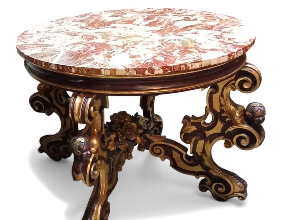 Round table made of gilded and ebony-finished wood - Rome, early 19th century: Round table made of gilded and ebony-finished wood - Rome, early 19th centuryHeight x diameter: 94 x 123 cmwith a base consisting of four scroll-shaped legs carved with leaf motifs, scrolls, and flora