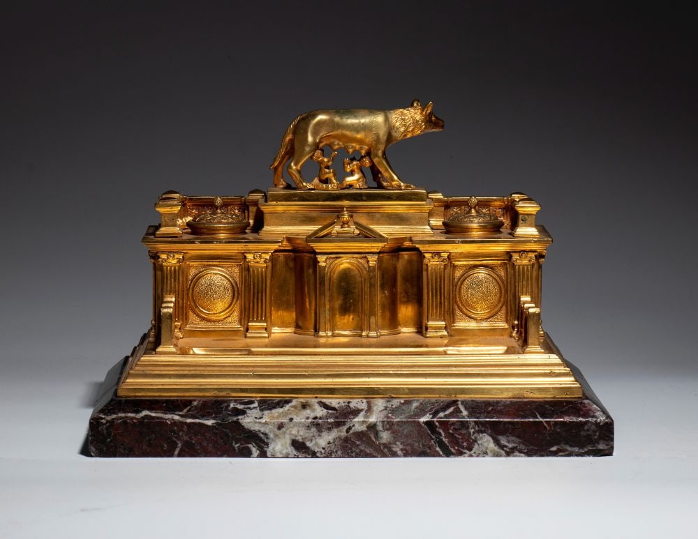 Gilded bronze inkwell: Gilded bronze inkwellHeight x width x depth: 19 x 30 x 21 cmRome, 19th centurya monumental desk inkwell, modeled after a neoclassical architectural structure, with facades punctuated by columns,