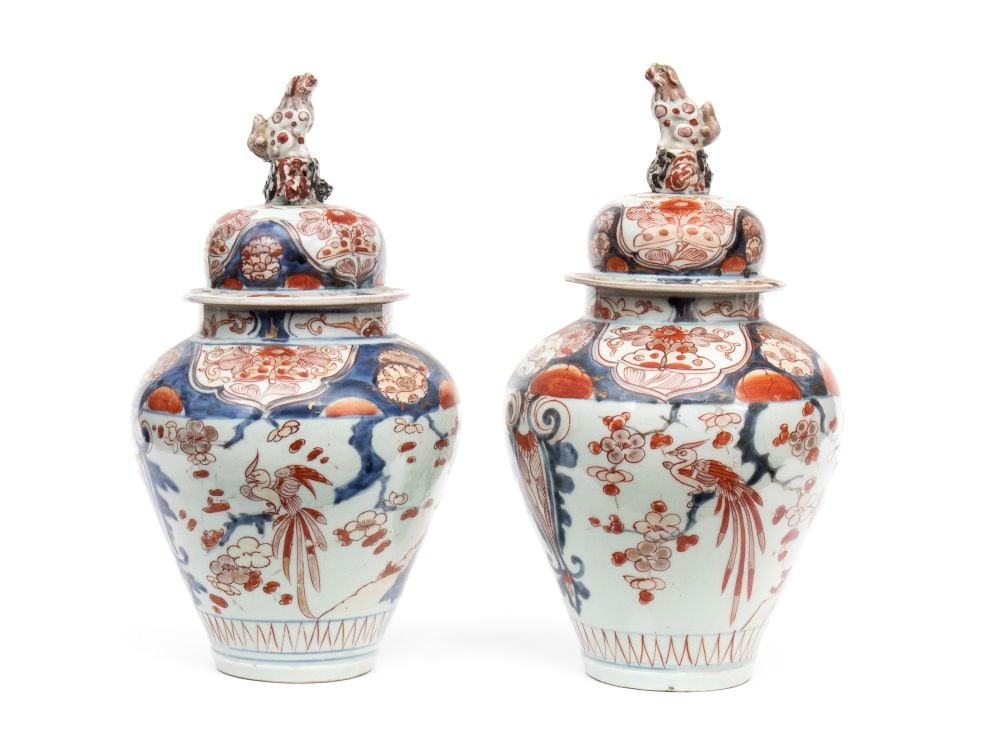 A pair of Covered Baluster Vases - China, Qing period: Height x diameter: 34 x 18 cm.Porcelain decorated in underglaze blue, iron-red and gilt, in the typical Imari palette.The baluster-shaped bodies are adorned with floral reserves featuring peonies and 
