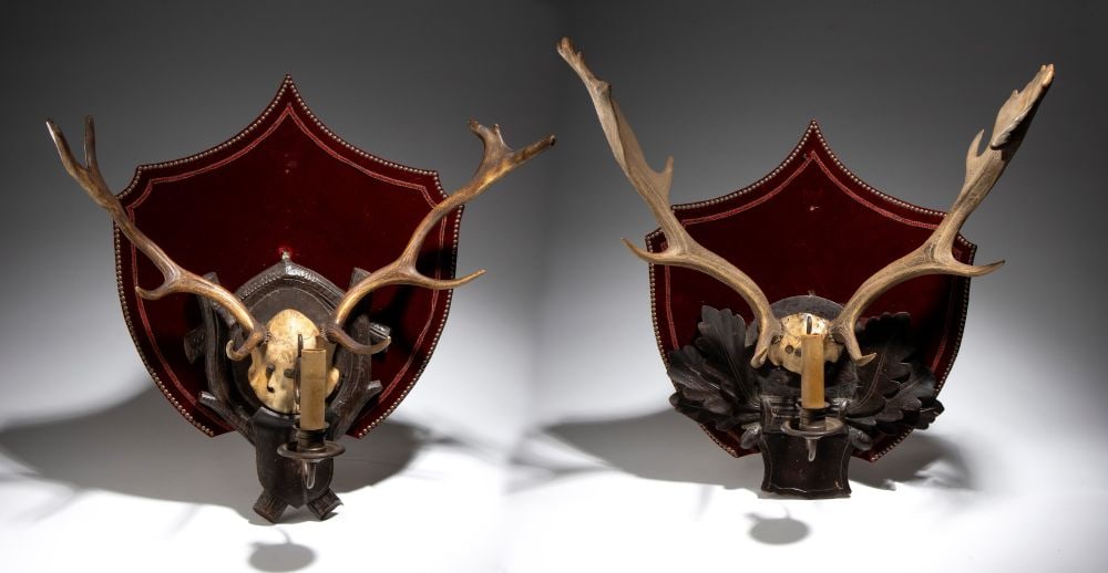 Pair of hunting-style wall sconces - Germany, late 19th century–early 20th century: Height x width x depth: 55 x 58 x 31 cm; 56 x 56 x 26 cmmade from deer antler trophies, mounted on large, contoured shields covered in burgundy red velvet.Item condition grading: **** good.The lot is 