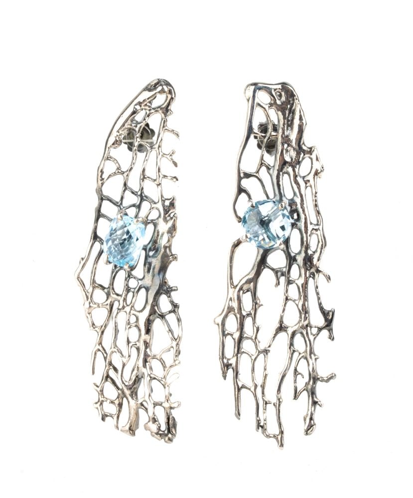 ISABELLA ASTENGO Blue topaz silver drop pair of earrings: A pair of earrings characterised by an organic, avant-garde artistic style. The main structure extends vertically, featuring an asymmetrical silver openwork pattern, reminiscent of the natural veins