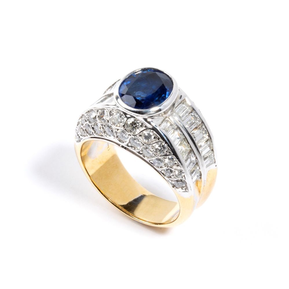 Sapphire diamond gold band ring: 18k yellow and white gold, set with an oval sapphire surrounded by baguette-cut and brilliant-cut diamonds. N. 01 oval-shaped sapphire, composite cut, estimated weight approx. 2.42 ct; round brilliant