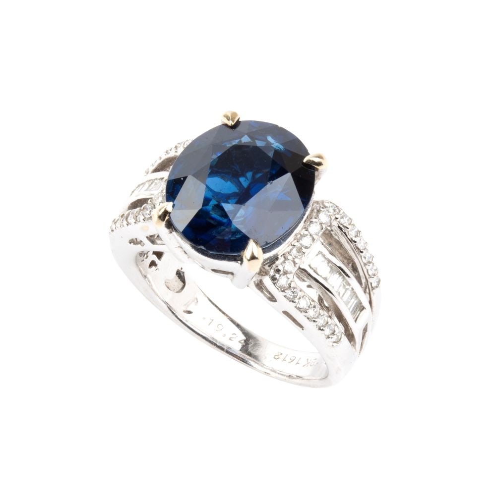 Blue sapphire diamond gold ring: 18k white gold, set with an oval sapphire, the shanks accented by diamnds. N. 01 oval-shaped sapphire, composite cut, estimated to weigh approx. 6.12 ct; brilliant-cut and baguette-cut diamonds