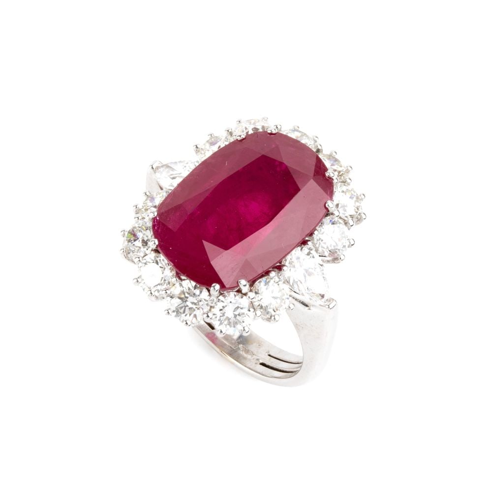 Burma ruby diamond gold ring: 18k white gold, set with a striking oval-shaped ruby, composite cut, weighing 9.30 ct, surrounded by 12 brilliant-cut diamonds and 2 pear-shaped diamonds, with an estimated total weight of approx.