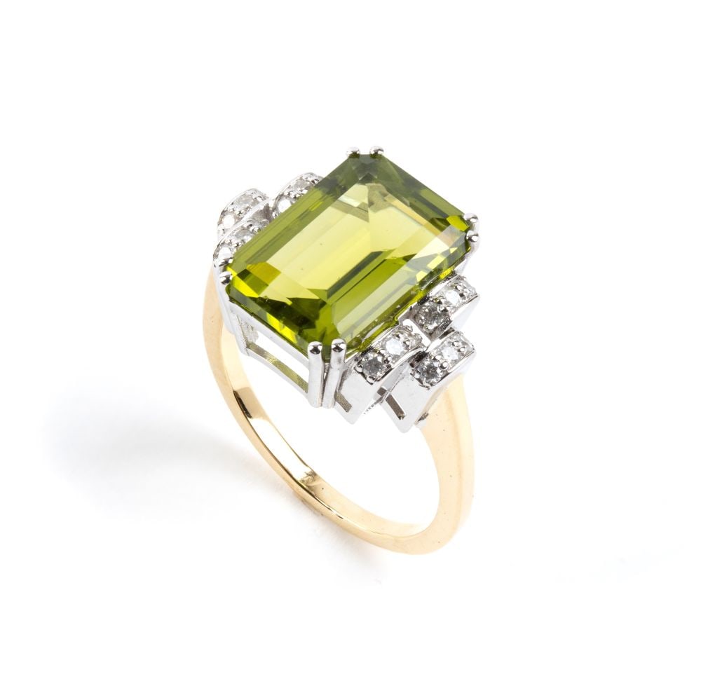 Peridot diamond gold ring: 18k yellow and white gold, set with a peridot estimated to weigh approx. 5.92 ct, flanked by round brilliant-cut diamonds estimated to have a total weight of approx. 0.21 ct, colour H, clarity I, as