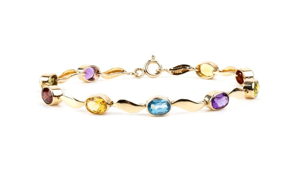 Multi-gemstone gold bracelet: 18k yellow gold leaf motif chain, separating colored gemstones (citrine quartz, blue topaz, garnet, peridot).Hallmarked "18k". Length: 18 cm. Weight: 9.1 g.