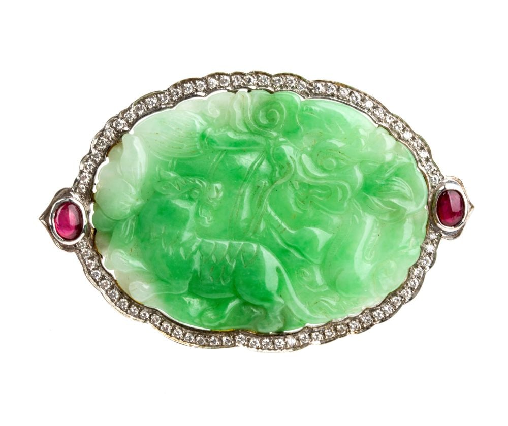 Green jade diamond ruby gold brooch: 18k white gold, set with a carved green jade slab depicting mythical animals, framed by a pair of cabochon-cut rubies and round brilliant-cut diamonds, estimated to weigh a total of approx. 0.70 ct,