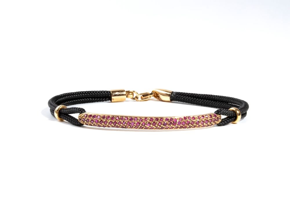 Gold pink corundum bracelet: a fabric cord with a central section and a clasp in 18k rose gold. The central bar is pave set with pink sapphire estimated to weight a total of approx. 0.80 ct, as gauged and graded in the