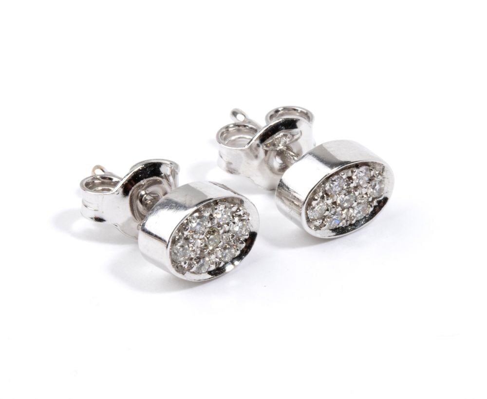 A pair of gold and diamond earrings: oval shaped, 18k white gold, with pave set round brilliant-cut diamonds, estimated to weigh a total of approx. 0.13 ct, G-H colour, SI clarity, as gauged and graded in the mount.Hallmarked