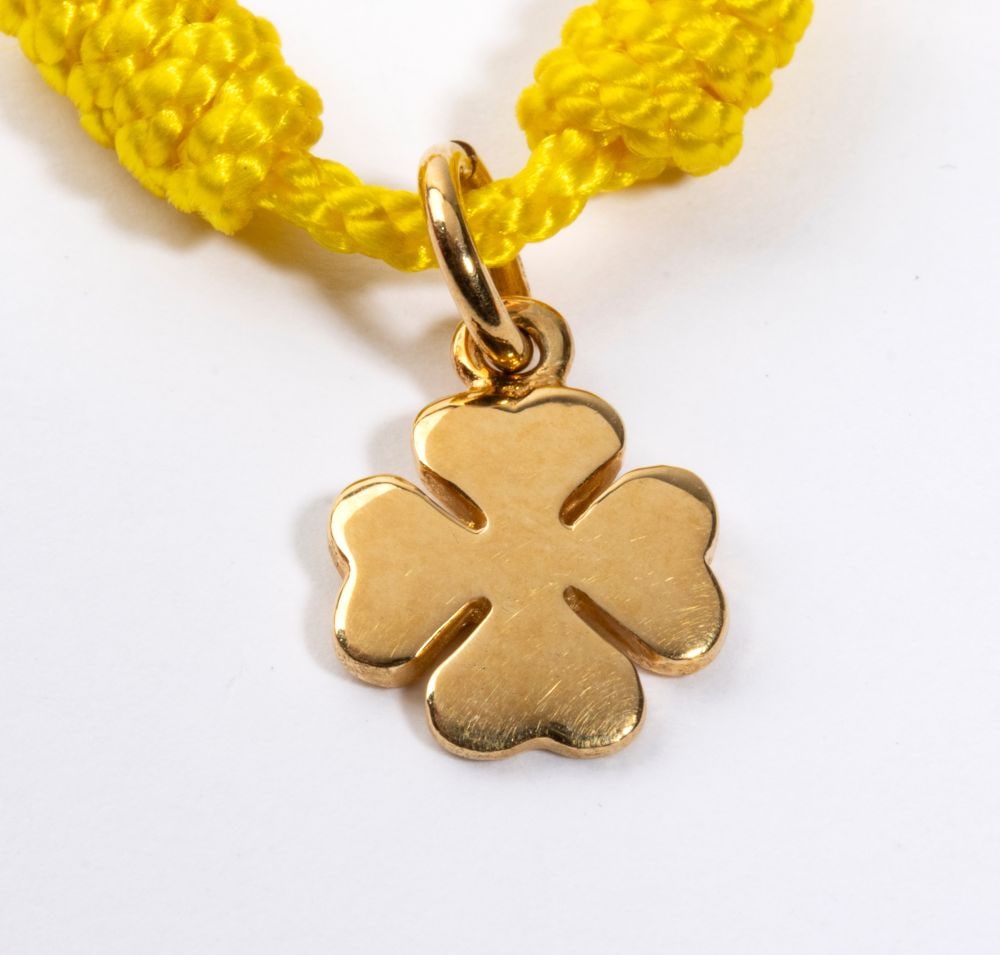 Bracelet with gold pendant: featuring an 18k white gold four-leaf clover shape, sospended from a fabric cord. Weight: 1.6 g.