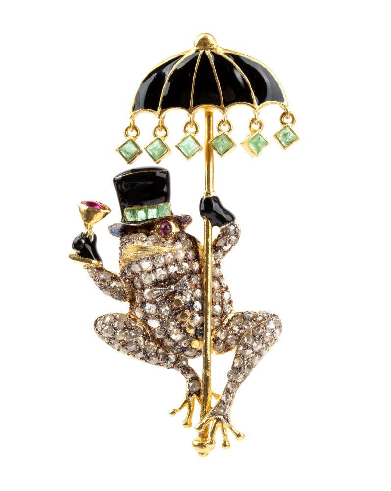 Brooch in gilded silver, gold, enamel, rubies, emeralds and diamonds: Gold-plated silver body and 14k yellow gold connecting hook; hat and parasol finished in glossy black enamel and decorated with emeralds; eyes and the cocktail in the right paw set with small rubies;
