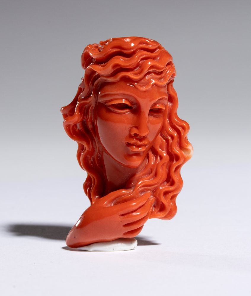 CARLO PARLATI Coral carving depicting a female figure: Entirely carved from a single branch of Cerasuolo coral (Corallium elatius) of exceptional chromatic quality.The composition depicts an elegant female bust with idealized features, her head gently inc