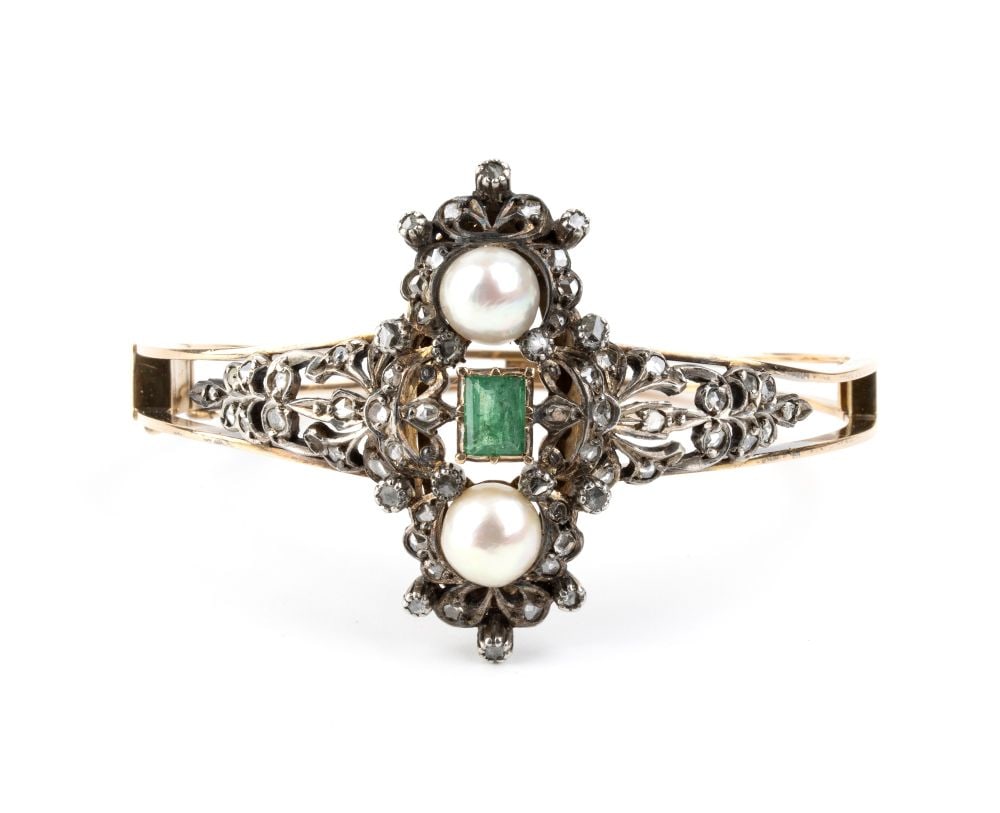 A rigid gold and silver hoop bracelet set with emerald, pearl and diamonds: 18k white gold, with a central openwork plant motifs, set with an emerald flanked by a pair of saltwater pearls and surrounded by rose-cut diamonds.Inner diameter: 5.5 cm. Weight: 28 g.