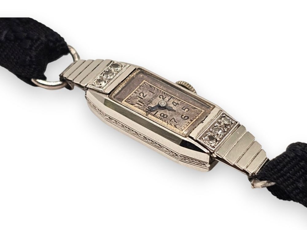 CALDERONI Art déco Lady platinum diamond wristwatch: Rectangular platinum case with 6 diamonds, silver dial signed “CALDERONI” with Arabic numerals, hinged case back stamped “63 MI” from the Fascist period, and fabric strap.