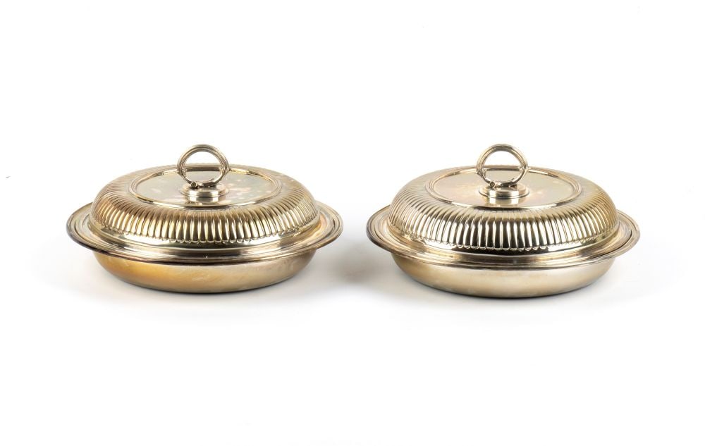 FRATELLI CACCHIONE A pair of Italian solid silver entrée dishes: circular in shape, each piece consists of a shallow base plate and a domed snap-on lid, both featuring a decoration of grooved bands and a central detachable ring-shaped knob.800/1000 silver, hallmark