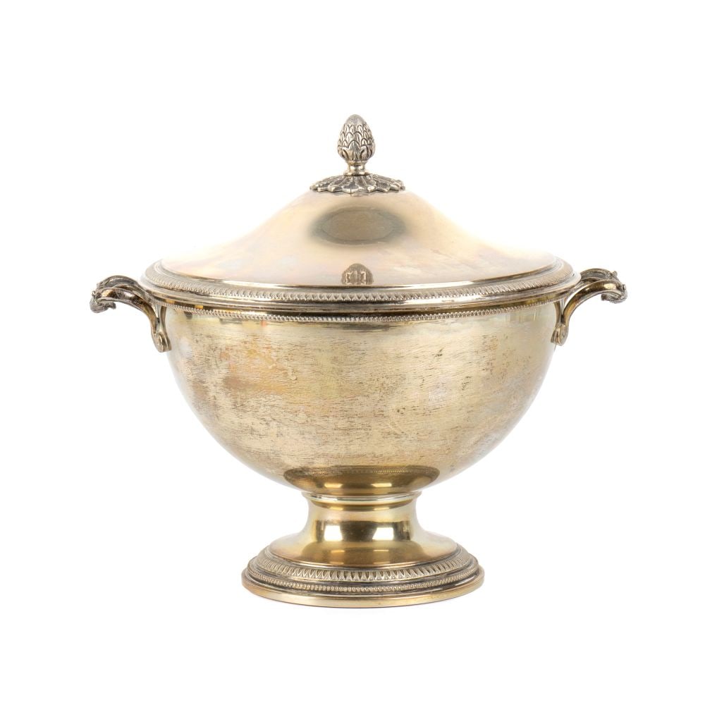 Italian soli silver tureen: Hemispherical in shape with a wide flared body, supported by a tall, circular, spool-shaped foot with a stepped base. The slip-on lid is topped by a pine cone-shaped handle. It features two side