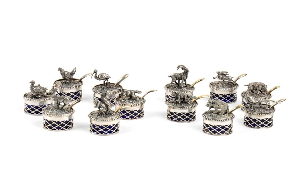 Set of 12 Italian solid silver place cards: oval in shape, containing blue glass, decorated with lids in the shape of various animals and each accompanied by a small spoon. Comes with a green velvet box.800/1000 silver, hallmarked "800’"