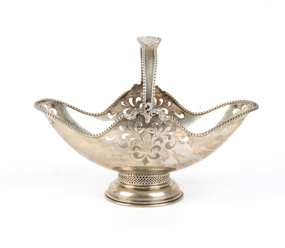 Italian solid silver basket: oval in shape, characterised by an undulating profile with a beaded rim. The side walls feature openwork with scroll motifs. Topped by a tall, fixed arched handle, also embellished with a double beade