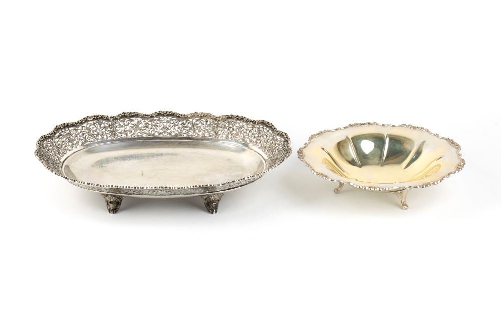Group of two solid silver baskets: - oval-shaped centrepiece with a wide, smooth rim, characterised by a tall, opulent openwork rim featuring a richly crafted, mixed-line design with scrollwork and foliage motifs, resting on