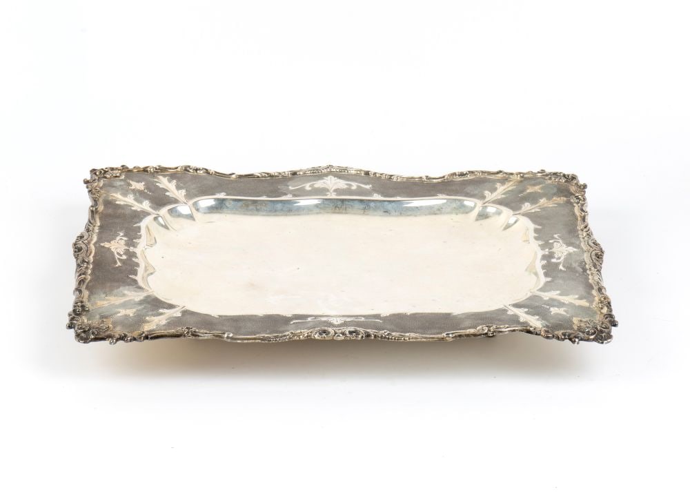 Italian solid silver serving tray: crafted with embossing and chiselling, rectangular in shape; the outer edge is shaped with undulating lines and finished with a rich embossed frame featuring volutes and rocaille motifs.800/1000