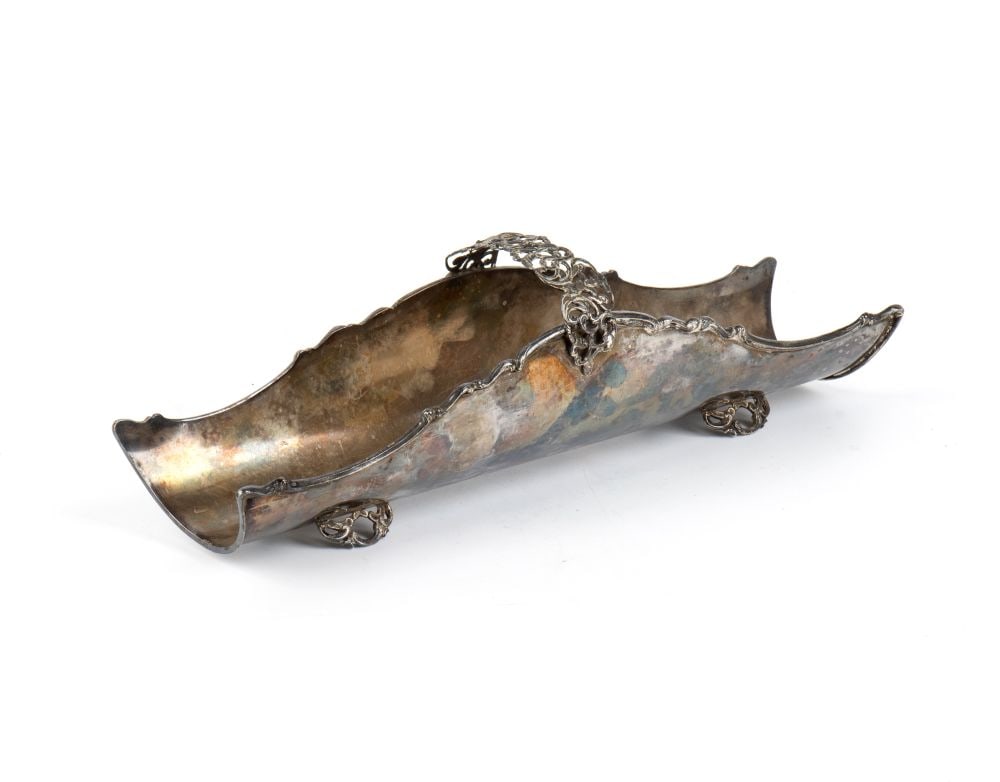 Italian solid silver breadstick holder: concave in shape, resembling a semi-cylinder open at both ends. At the centre of the piece stands a small openwork arch featuring rocaille scrolls and plant-inspired motifs.800/1000 silver,