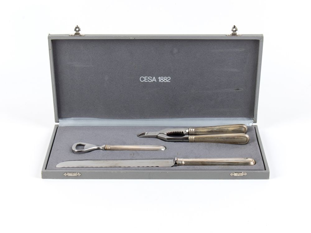 Silver service: consisting of: a bread knife with a long serrated blade, a nutcracker with double handles and a serrated jaw, and a lever-action bottle opener. Includes the original box.800/1000 silver, hallmarked
