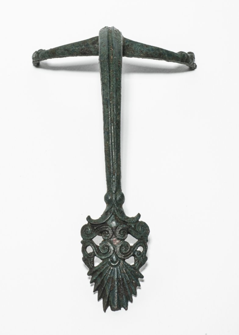 A bronze Oinochoe handle Greece, 5th century BC: A bronze Oinochoe handle Greece, 5th century BC; height cm 14 (6â€™â€™); Ribbed arched handle with two stretched panthers above and terminating with an inverted palmette and volutes. Dark gr