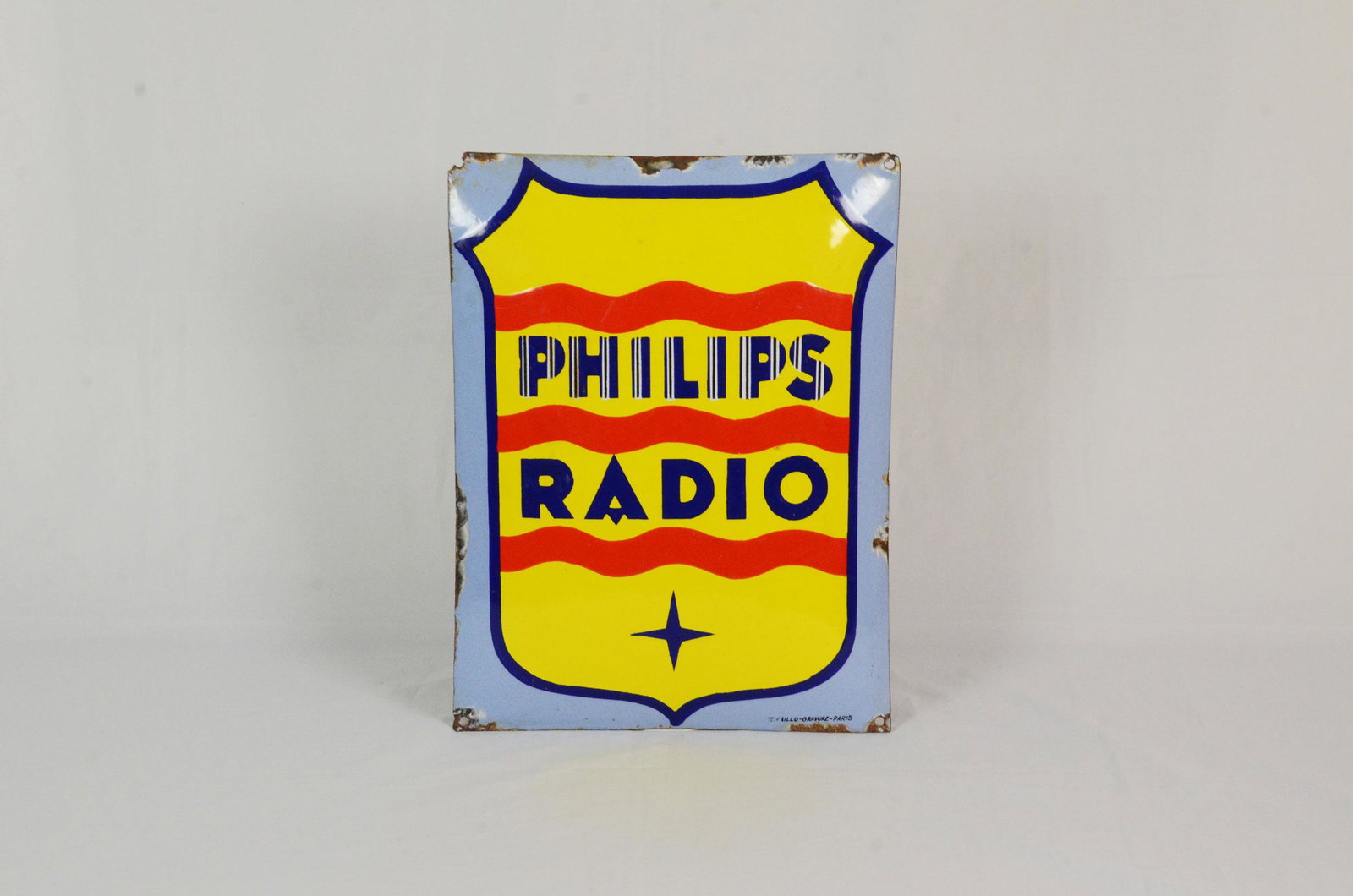 Curved enamel sign Philips Radio: This curved Philips Radio enamel sign is in good condition. 3 of the 4 mounting holes remaining with one missing due to a broken corner. Some enamel missing around the edge and corners. 40 x 30,5 cm.