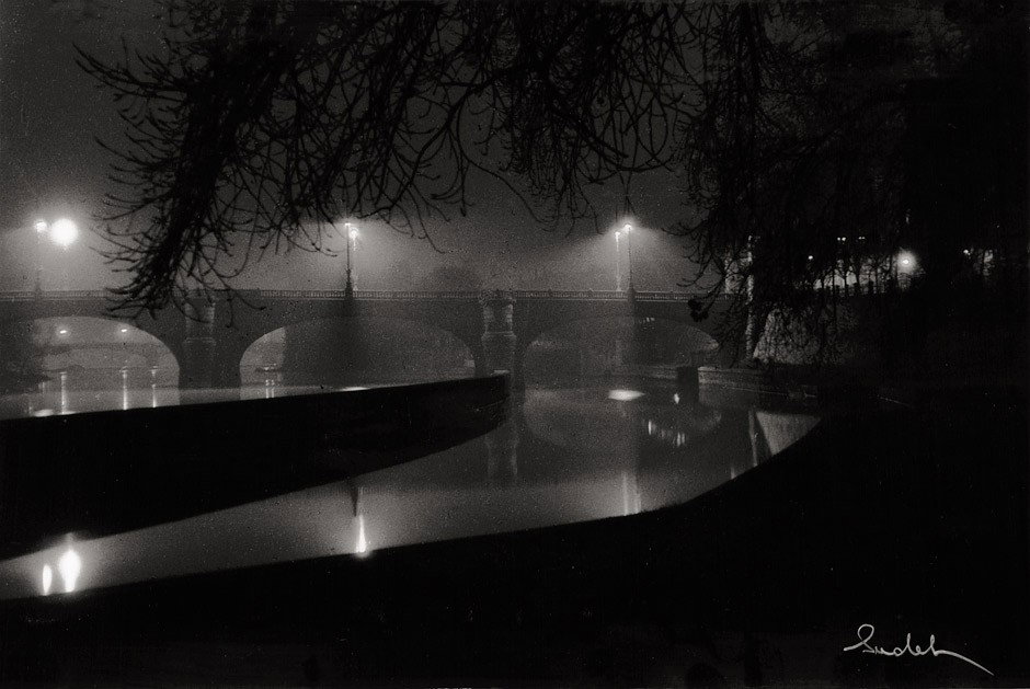 Sudek, Josef: Moldau bridges at night: Moldau bridges at night. 1963. Vintage ferrotyped gelatin silver print. 18,2 x 24 cm. Signed in white ink in lower right corner, mounted to original cream board (slight foxing); photographer's sta