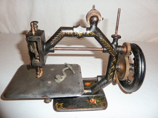 EARLY PAINT DECORATED MINIATURE SEWING MACHINE: SHOWING A EARLY PAINT DECORATED MINIATURE SEWING MACHINE . WORKING ORDER . MEASURES 12" WIDE BY 8" TALL AND 4 1/2" DEEP . AS FOUND ESTATE CONDITION.PLEASE USE PHOTOS AS PART OF THE DESCRIPTION. THE AB