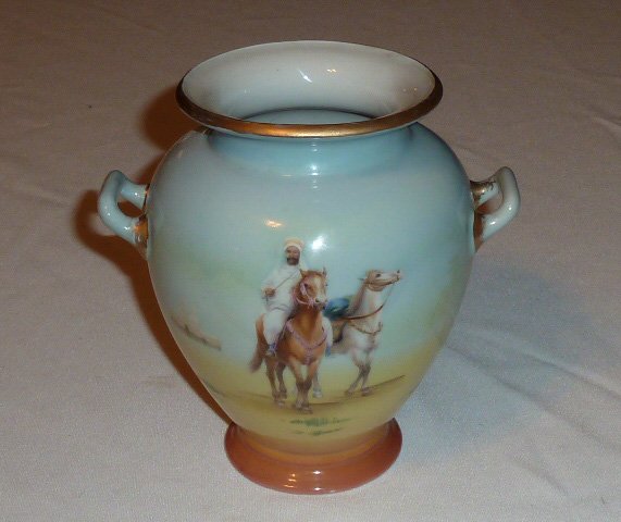 ROYAL BAYREUTH ARABIAN HORSEMEN 2 HANDLE VASE: SHOWING A SIGNED ROYAL BAYREUTH TWO HANDLE VASE. FRONT DESIGN CONSISTS OF AN ARABIAN HORSEMEN LEADING A RIDERLESS HORSE. BACK DECORATION SHOWS A HORSEMEN RIDING IN THE DESERT. GOLD TRIM WITH BLUE MAKE