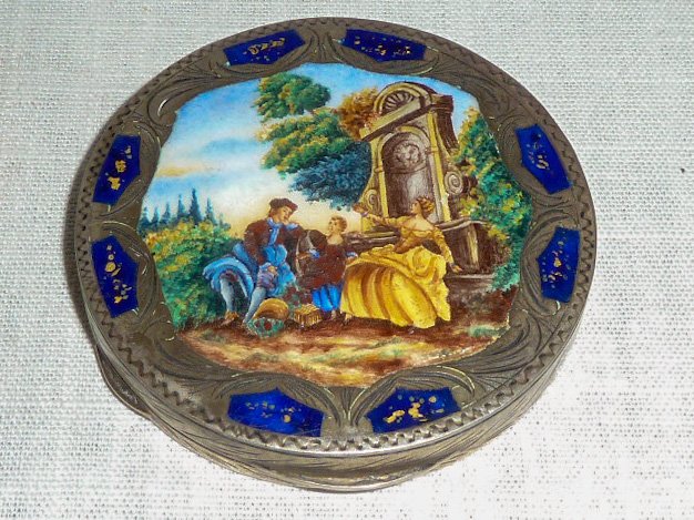 Antique Ornate Silver & Enamel Compact: Cover is a country side scene: Man woman and child sitting by a large fountain , with a border of chased silver and blue enamel. Back is a chased flower mandala . Makers mark on the interior top. Look