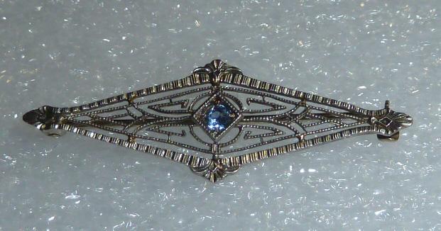 14kt White Gold Art Deco Filigree Diamond Shape Pin: Sweet looking Art Deco filigree pin with intricate wire work design. Blue stone adornes the center. Measures 1 1/2" long by 1/2" high. Weighs .9 dwt. . Christmas is coming , is this on your Holiday Wi
