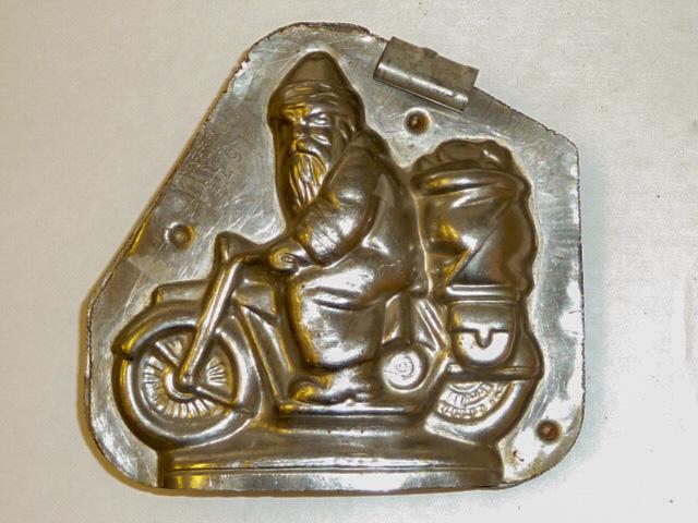 Early Chocolate Mold Santa Riding Motor Cycle Holland: Santa Kris Kringle Chocolate Mold, Santa Is riding A motorcycle. Piece is signed â€œKris Kringle” and Stamped Vormenfabriek Tilborg â€“ Holland #15291. Mold Measures 5” by 5&rdquo