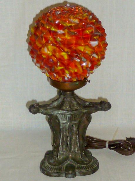 Art Deco Lamp w/Three Nudes End of Day Shade: Ornate cast metal base with three semi-nude females holding Czech end-of-day multi-colored globe/shade. Excellent working condition. Measures 15” tall and 7” wide. This lamp will be the ce