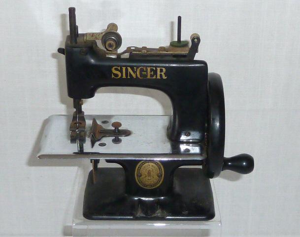 Singer Child's Sewing Machine Antique 1920's: Singer 1920's Child's sewing machine . Machine measures 6 “ high by 7” to its handle . Machine is iron with black enamel . Gold Singer Decal labels are good . Metal medallion in tact . In