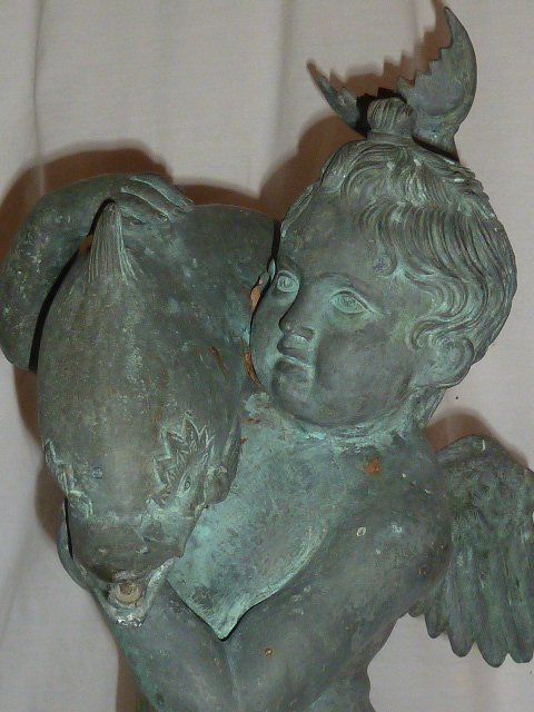 BRONZE CHERUB CARRING FISH FOUNTAIN: SHOWING A BRONZE CHERUB CARRYING A FISH FOUNTAIN MEASURES 24" TALL . AS FOUND ESTATE CONDITION.PLEASE USE PHOTOS AS PART OF THE DESCRIPTION. THE ABSENCE OF A CONDITION REPORT DOES NOT GUARANTEE EXCELL