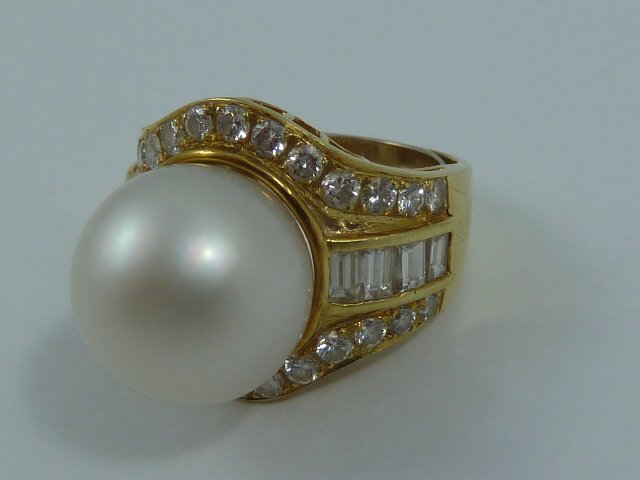 18KT GOLD FASHION RING CENTER SET CULTURED PEARL: SHOWING A 18KT YELLOW GOLD FASHION RING ,CENTER SET WITH A CULTURED PEARL . FLANKED ON EACH SIDE BY 4 CHANNEL SET BAGUETTES. RING IS BORDERED BY 25 FULL CUT DIAMONDS .TOTAL DIAMOND WEIGHT IS 2.08 CTS.